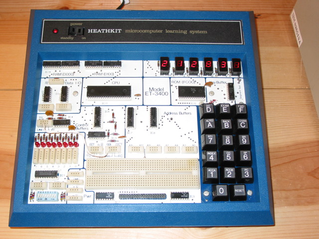 A Heathkit ET-3400 Microprocessor trainer turned on.  There is a wire connecting the LINE tie point to the NMI tie point.  The display shows 212831.