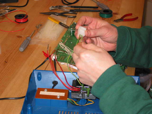 Hands inserting a wire that comes from a transformer into a molex 6-pin plug