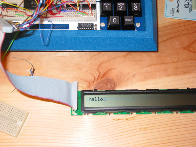 The bottom part of a Heathkit ET-3400A Microprocessor trainer which has some circuitry on it, connected to a two-line LCD display module.  The module shows hello_