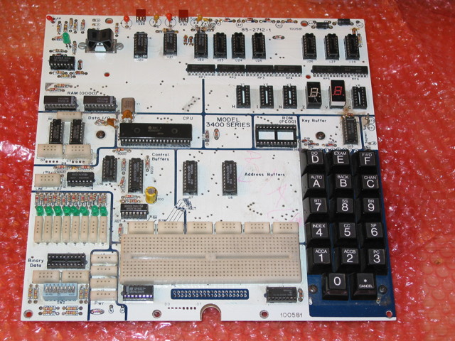 A mostly-populated Heathkit ET-3400A board with no case, all keys present, 4 seven-segment displays missing, ROM missing, and all indicator LEDs present, but they're green instead of the usual red
